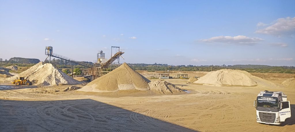 Vista do porto de areia P3 da Dibasico em em Iperó. A imagem mostra montes de areia e um caminhão do lado inferior direito.